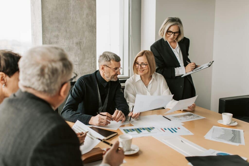 People working together in a team around a desk in an office and smiling, representing the positive effects of good silo management in an organizaiton.