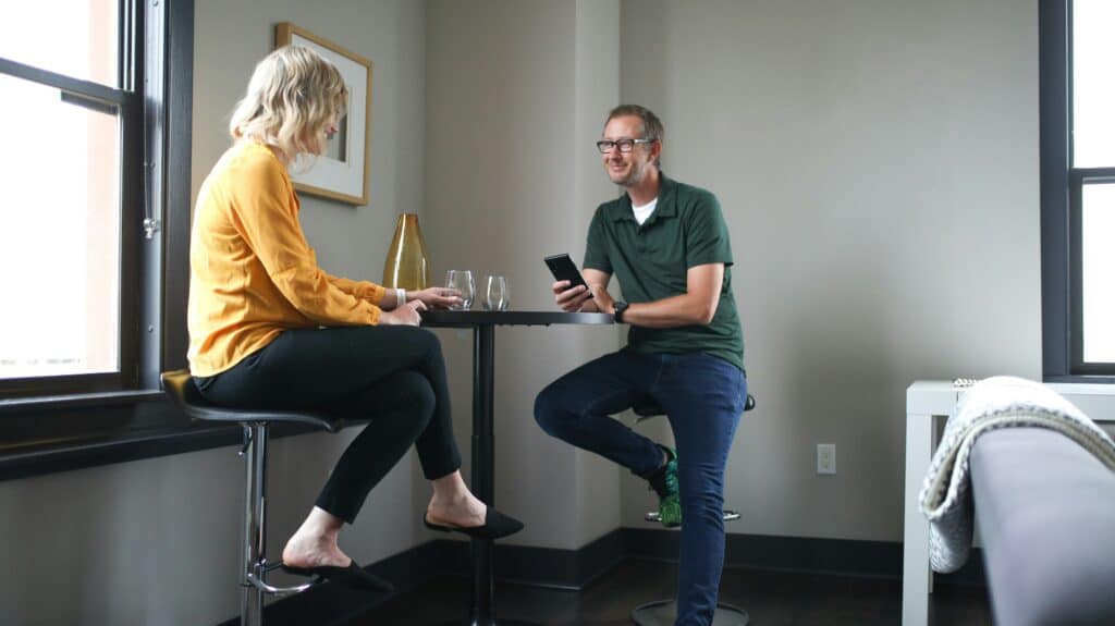 woman in yellow top and man in green shirt in office at table discuss enterprise knowledge management