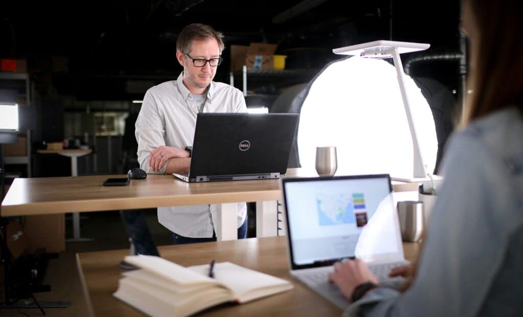 man at a standing desk on his laptop looking at healthcare knowledge management 