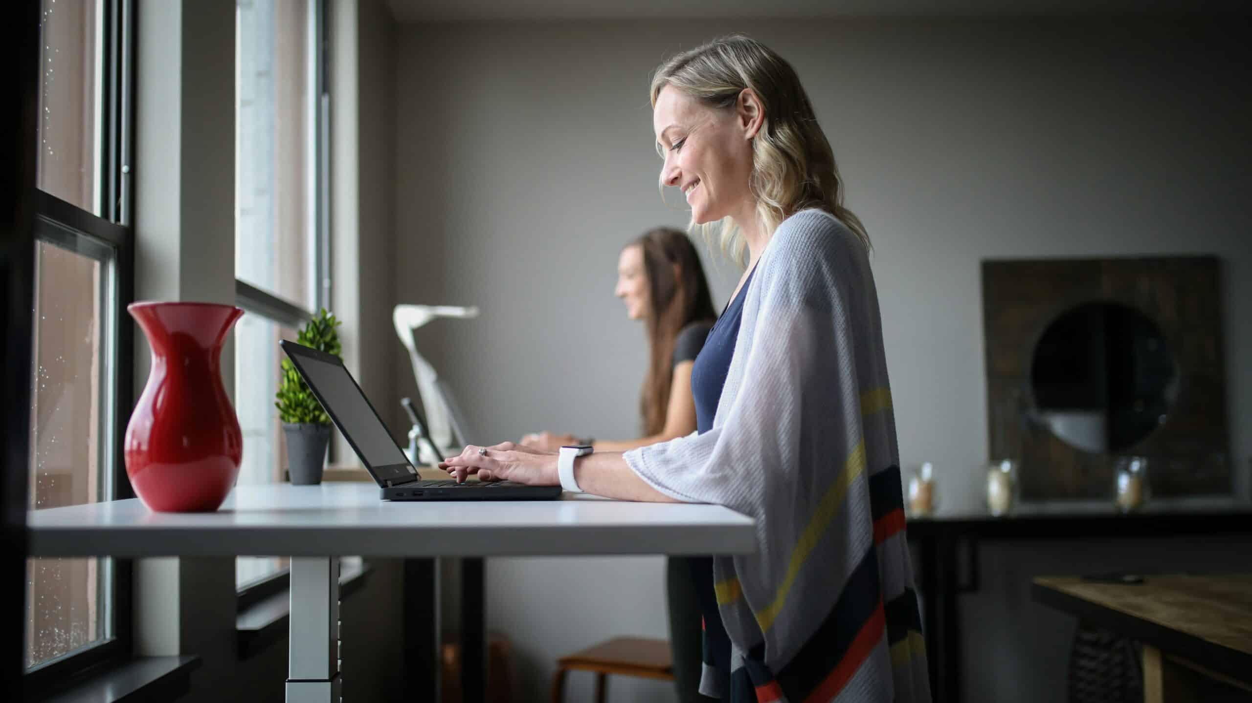 Blonde woman at standing desk looking at AI for market intelligence