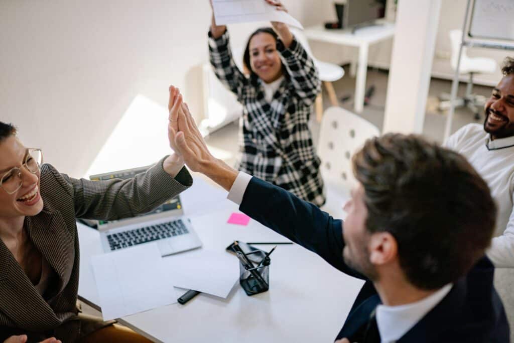 colleagues high fiving each other in an office after a successful Product launch, after leveraging AI-powered consumer and market insights
